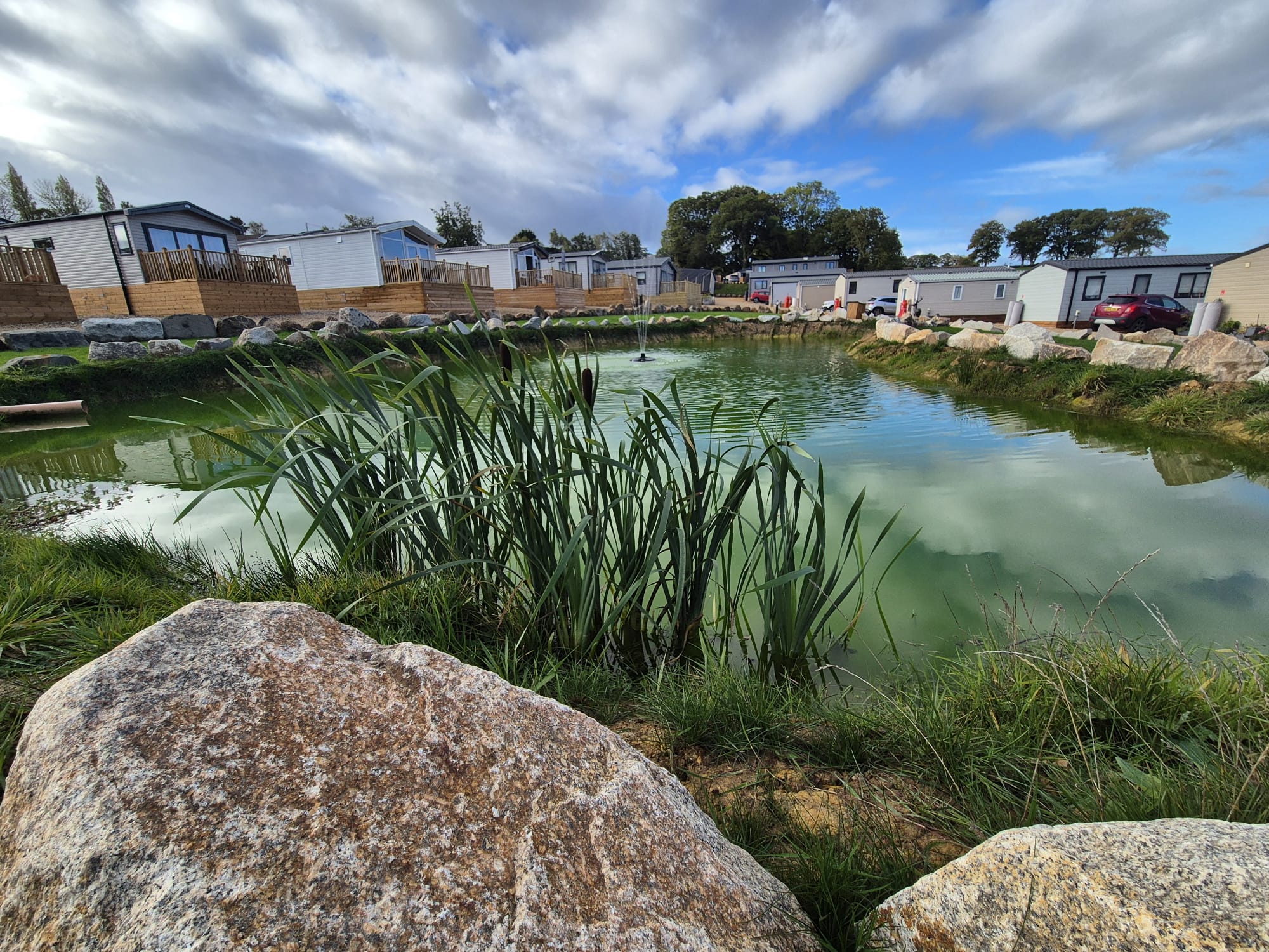 Site image closer shot of pond with caravans in background